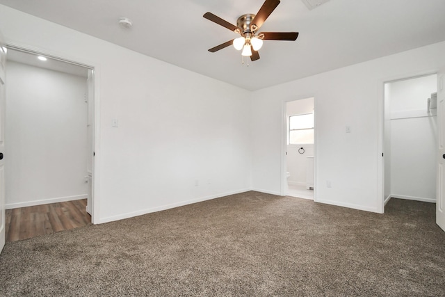 unfurnished bedroom featuring a closet, baseboards, a spacious closet, carpet, and ensuite bath