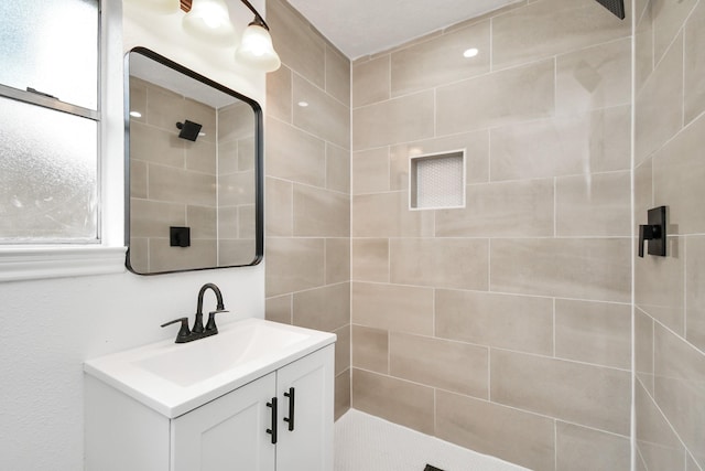 bathroom with a tile shower and vanity