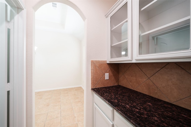 bar with arched walkways, baseboards, decorative backsplash, and light tile patterned floors