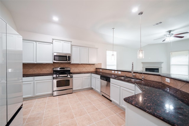 kitchen featuring visible vents, appliances with stainless steel finishes, tasteful backsplash, a sink, and a glass covered fireplace