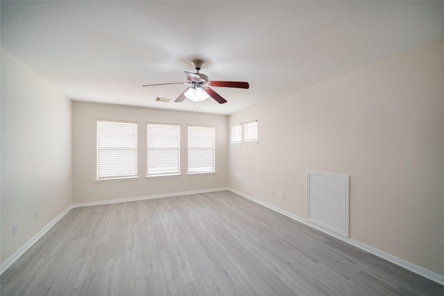 empty room featuring baseboards, ceiling fan, wood finished floors, and visible vents