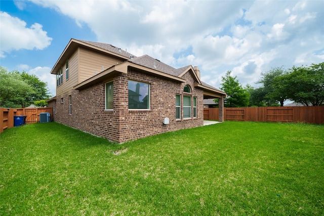 rear view of property featuring a fenced backyard, a yard, and brick siding