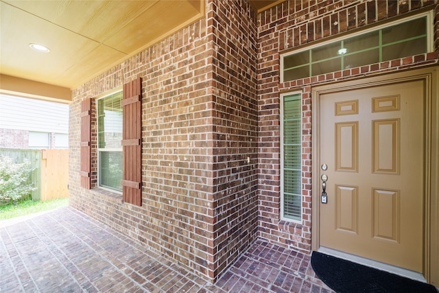 view of exterior entry featuring brick siding and a porch