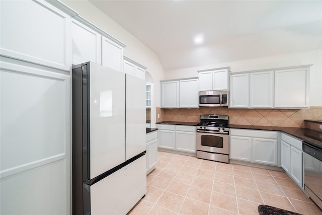 kitchen with white cabinets, dark countertops, appliances with stainless steel finishes, and decorative backsplash