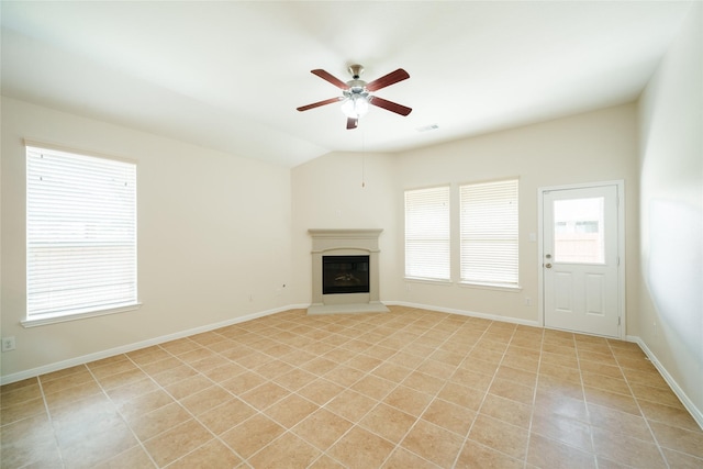 unfurnished living room featuring a glass covered fireplace, baseboards, ceiling fan, light tile patterned floors, and vaulted ceiling