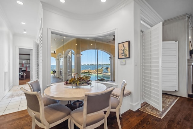 dining space featuring crown molding, recessed lighting, a water view, and wood finished floors