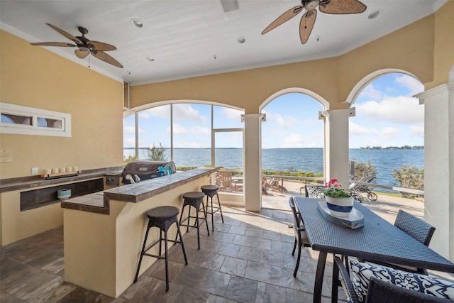 view of patio / terrace with a water view, ceiling fan, exterior kitchen, and outdoor wet bar