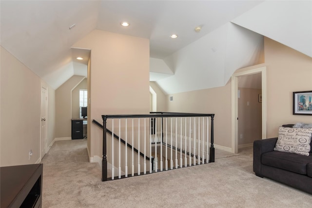 interior space featuring carpet floors, baseboards, vaulted ceiling, and an upstairs landing