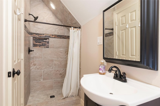 bathroom with a sink, vaulted ceiling, and tiled shower