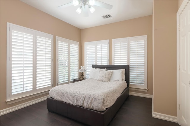 bedroom with visible vents, baseboards, dark wood-type flooring, and ceiling fan