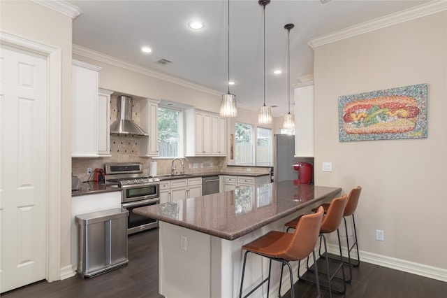 1900 Vermont St Unit B, Houston, TX 77019 - kitchen with wall chimney range hood, appliances with stainless steel finishes, a peninsula, white cabinetry, and crown molding