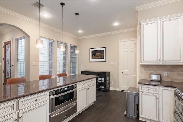 kitchen featuring visible vents, arched walkways, dark wood finished floors, white cabinets, and a warming drawer