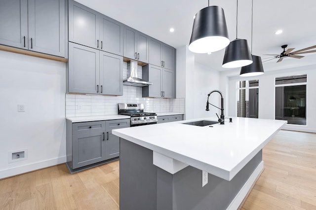 1707 Milby St, Houston, TX 77003 - kitchen featuring wall chimney range hood, gas range, a sink, gray cabinetry, and light wood-style floors