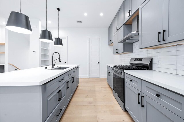 1707 Milby St, Houston, TX 77003 - kitchen with wall chimney range hood, stainless steel range with gas stovetop, tasteful backsplash, gray cabinetry, and a sink