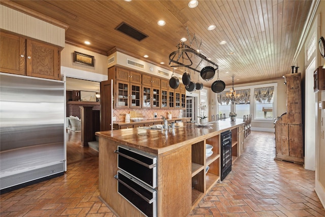 102 S R St, La Porte, TX 77571 - kitchen featuring stainless steel built in fridge, open shelves, a chandelier, beverage cooler, and brick flooring