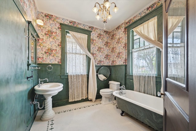 2614 Stanford St, Houston, TX 77006 - bathroom with a wainscoted wall, wallpapered walls, a soaking tub, a chandelier, and toilet