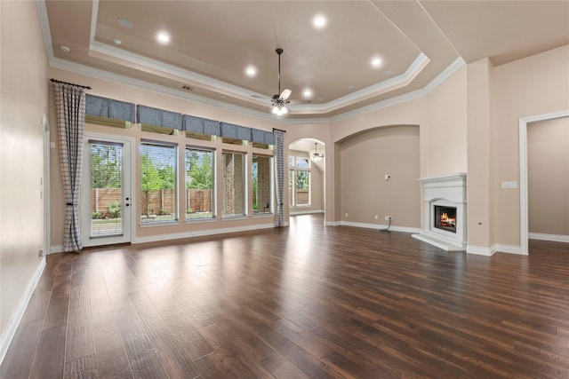15306 Guava Vis, Conroe, TX 77302 - unfurnished living room with crown molding, a raised ceiling, a ceiling fan, arched walkways, and baseboards