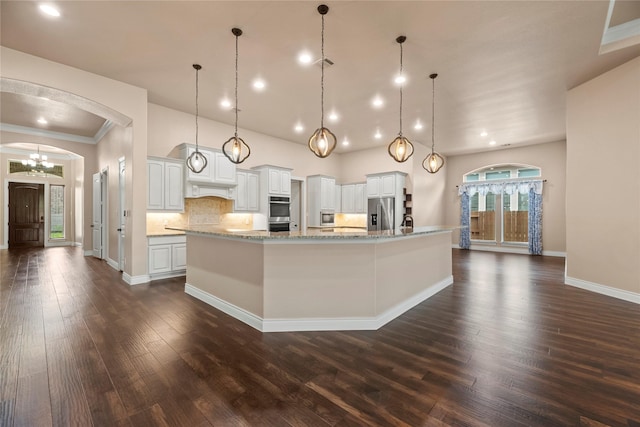 15306 Guava Vis, Conroe, TX 77302 - kitchen with appliances with stainless steel finishes, arched walkways, dark wood finished floors, a spacious island, and white cabinets