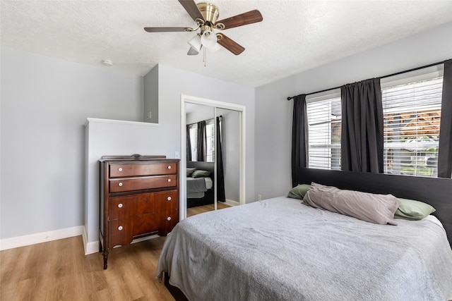 bedroom featuring a closet, a textured ceiling, wood finished floors, and multiple windows