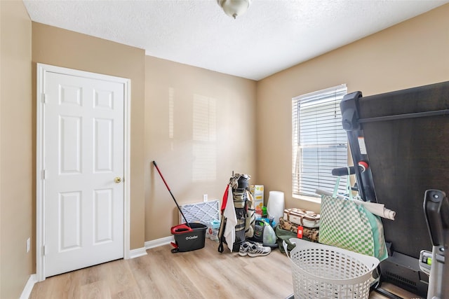 game room featuring baseboards, a textured ceiling, and wood finished floors