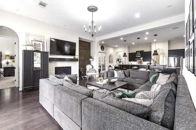 2502 Crossvine Dr, Katy, TX 77494 - living room featuring visible vents, an inviting chandelier, a glass covered fireplace, dark wood-type flooring, and arched walkways