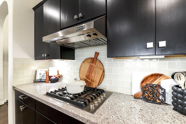 2502 Crossvine Dr, Katy, TX 77494 - kitchen featuring decorative backsplash, range hood, dark cabinetry, and stainless steel gas cooktop