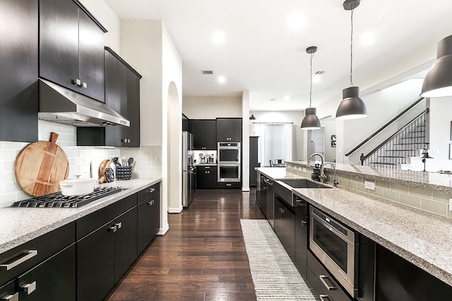 2502 Crossvine Dr, Katy, TX 77494 - kitchen with under cabinet range hood, stainless steel appliances, dark cabinetry, and a sink