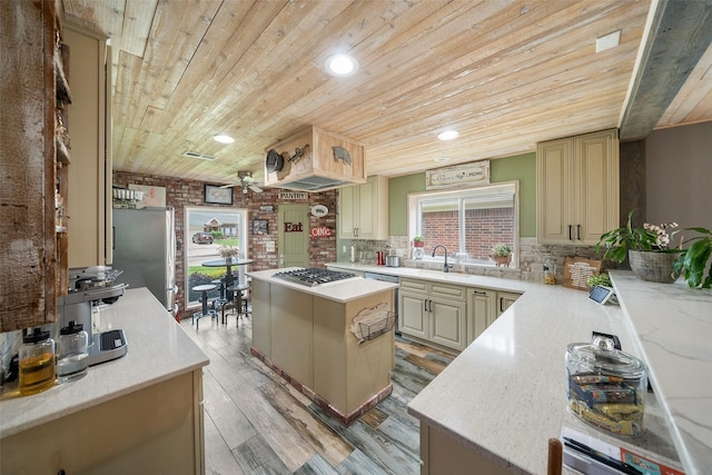 kitchen with appliances with stainless steel finishes, wooden ceiling, cream cabinetry, and a center island