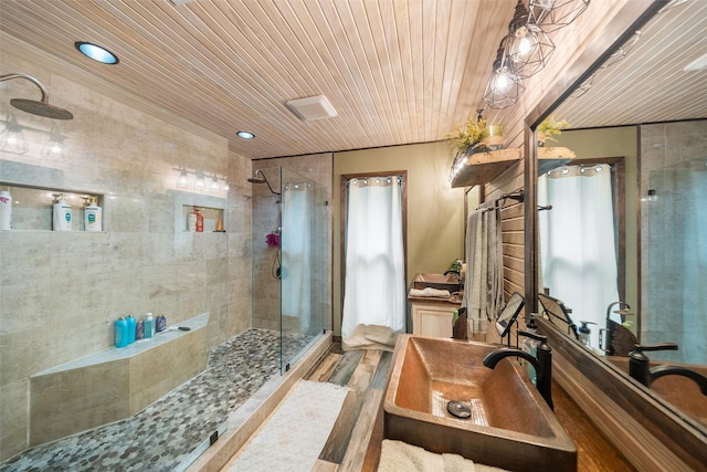 bathroom featuring a sink, wood finished floors, wooden ceiling, and tiled shower