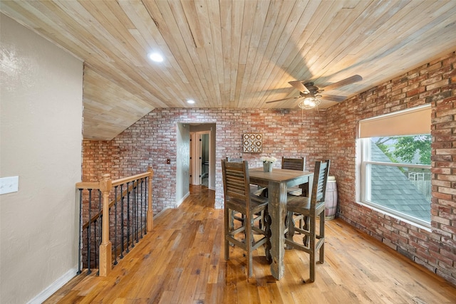 dining room featuring a ceiling fan, brick wall, wooden ceiling, baseboards, and light wood-style flooring