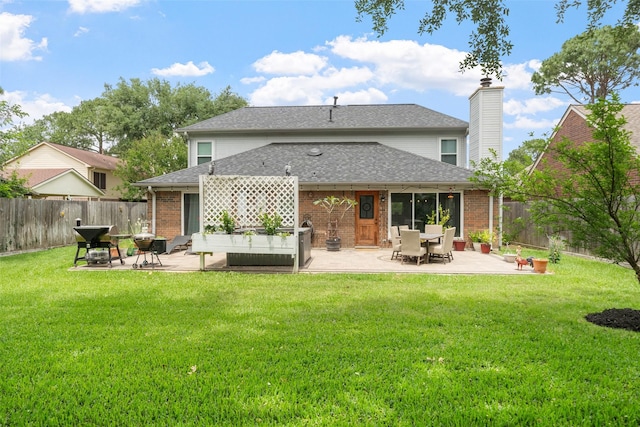 back of house featuring a chimney, a lawn, a fenced backyard, a patio, and a shingled roof