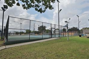 view of tennis court featuring a lawn and fence