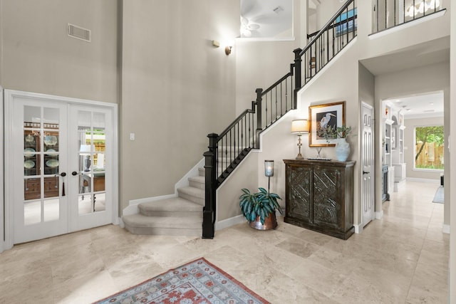 entryway with stairs, a high ceiling, baseboards, and french doors