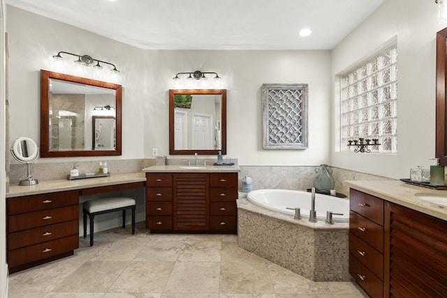 bathroom featuring a sink, a bath, and two vanities