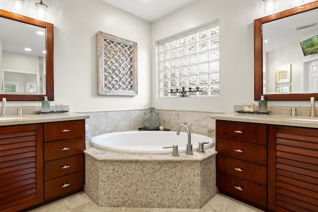 full bathroom featuring visible vents, a sink, a bath, and two vanities