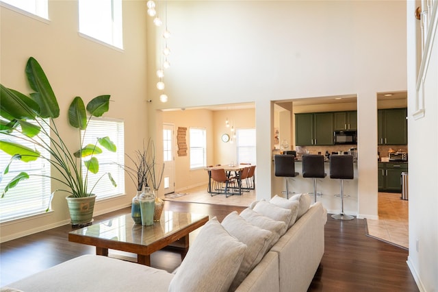 living room with a healthy amount of sunlight, a high ceiling, and dark wood finished floors