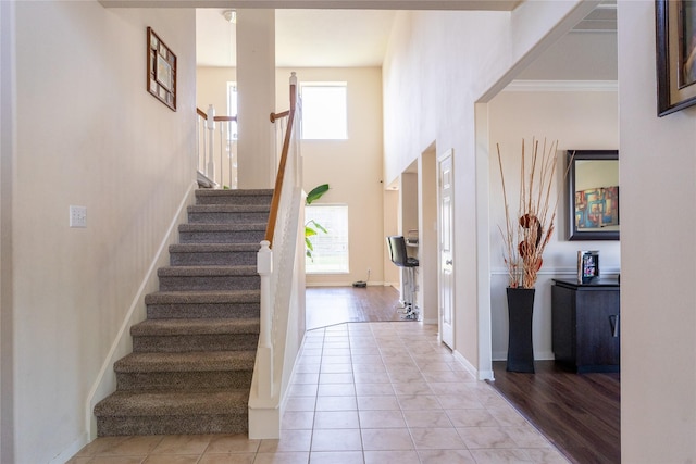 entrance foyer with baseboards, light tile patterned flooring, and stairway