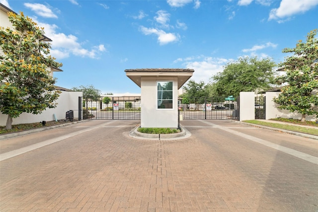 view of road with a gate, a gated entry, and curbs