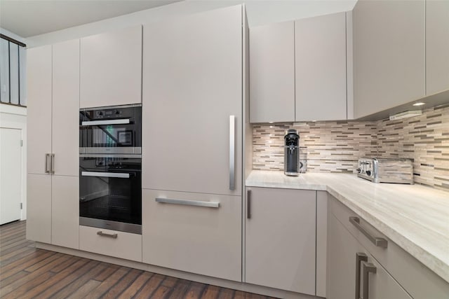 kitchen with tasteful backsplash, dark wood finished floors, light countertops, a toaster, and multiple ovens