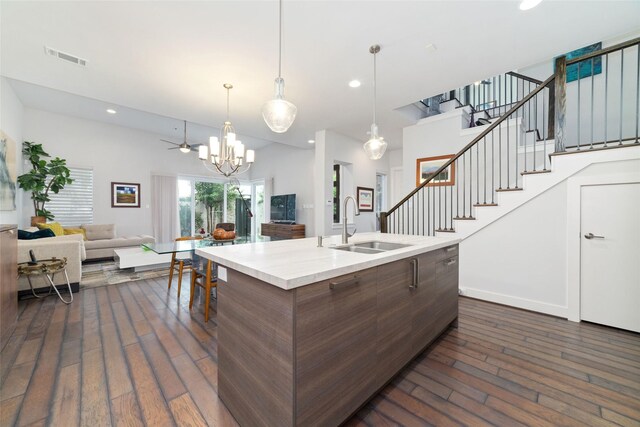 kitchen with dark wood-style flooring, an inviting chandelier, a sink, light countertops, and open floor plan