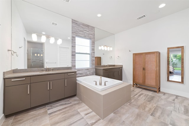 bathroom featuring two vanities, visible vents, plenty of natural light, and a sink