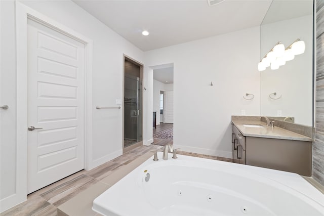 full bathroom featuring a jetted tub, baseboards, a stall shower, and vanity