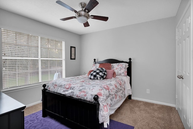 carpeted bedroom featuring baseboards, ceiling fan, and multiple windows