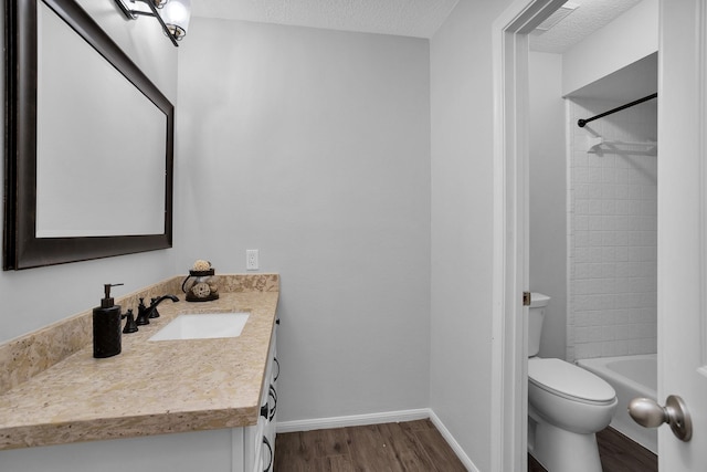 full bathroom featuring vanity, toilet, a textured ceiling, baseboards, and wood finished floors