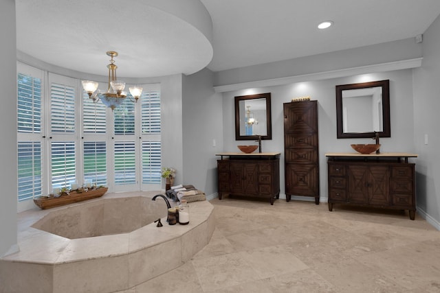 bathroom featuring a notable chandelier, recessed lighting, baseboards, two vanities, and a bath