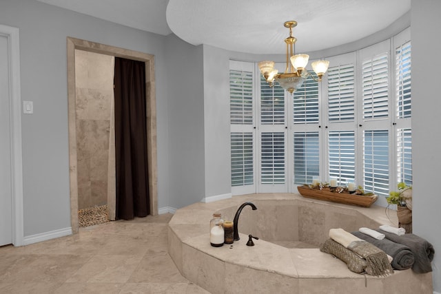full bath featuring baseboards, an inviting chandelier, a tile shower, and a bath