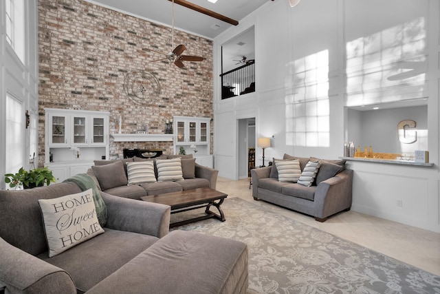 tiled living room featuring a towering ceiling, a fireplace, and ceiling fan