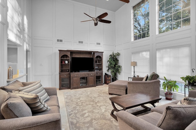 living area with a ceiling fan, high vaulted ceiling, visible vents, and a decorative wall
