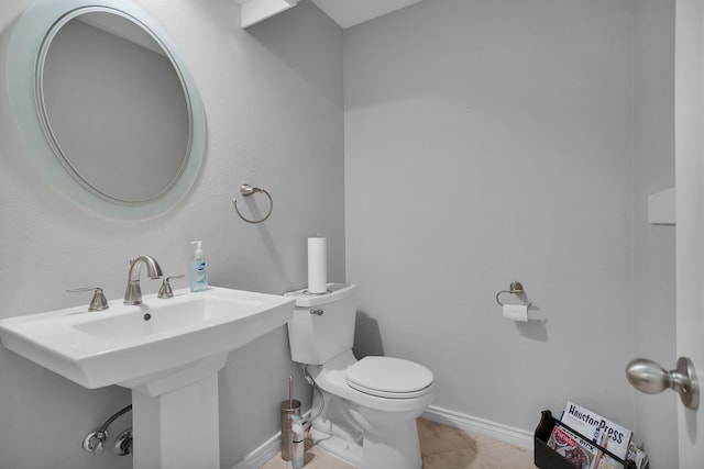bathroom with toilet, baseboards, a sink, and tile patterned flooring