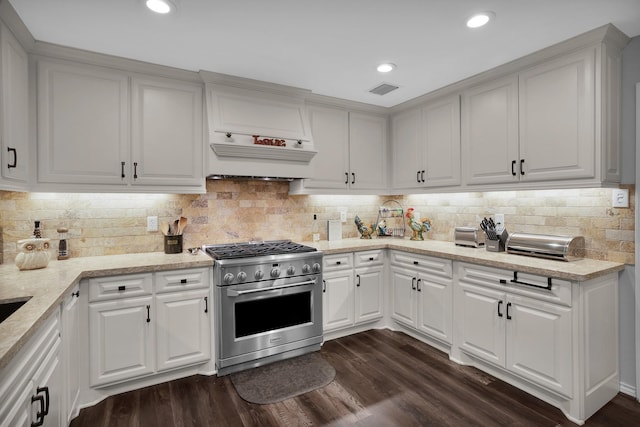 kitchen with white cabinets, custom exhaust hood, visible vents, dark wood-style floors, and high end stainless steel range oven